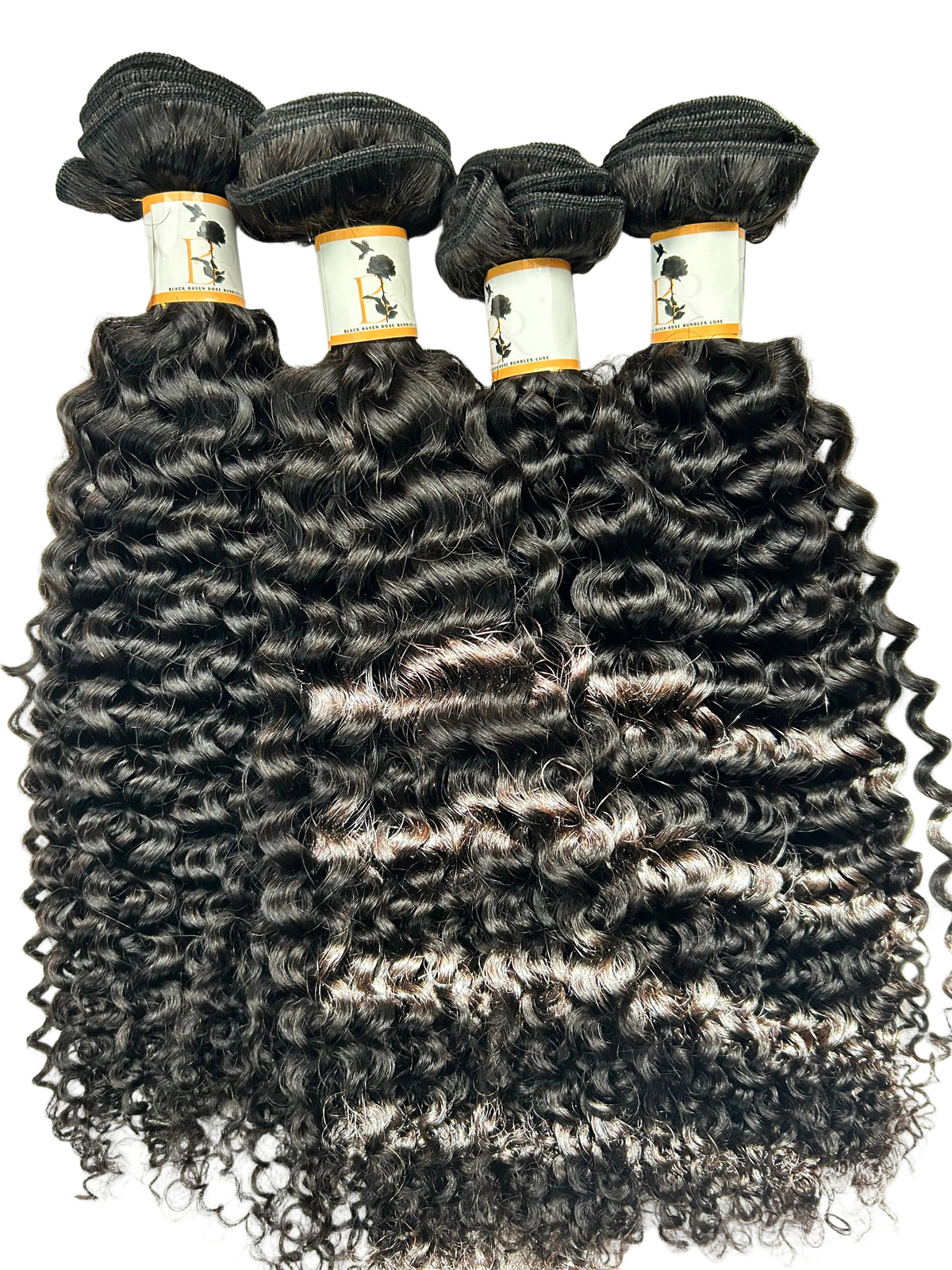 Four bundles of dark brown to black curly hair weave extensions laid flat on a light gray textured background.
