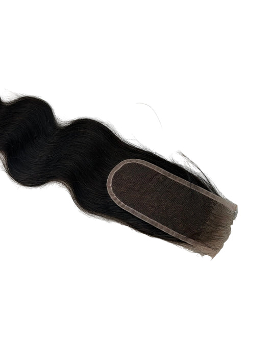 A single dark brown to black wavy hair extension piece with a lace base, laid flat on a textured off-white surface.