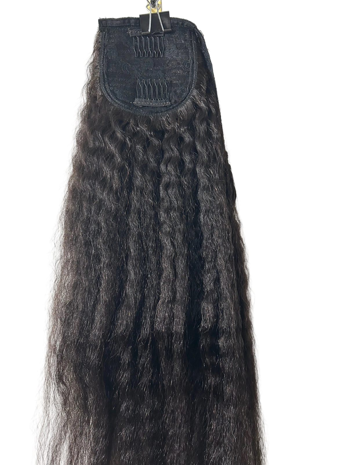 A long, dark brown to black Kinky Straight hair extensions shown hanging from a metal clip against a plain white background.